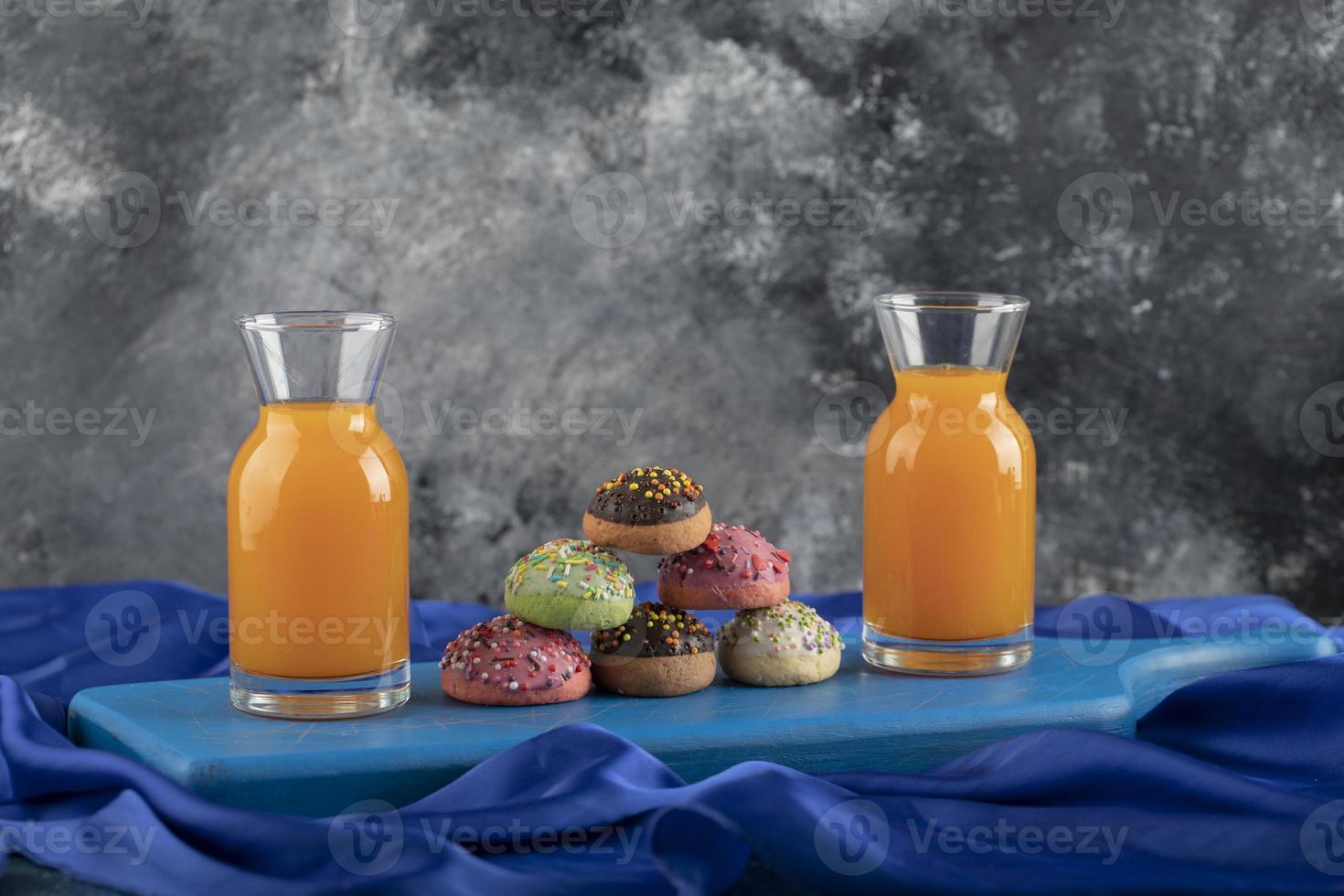 Colorful sweet doughnuts with glass jars of juice photo