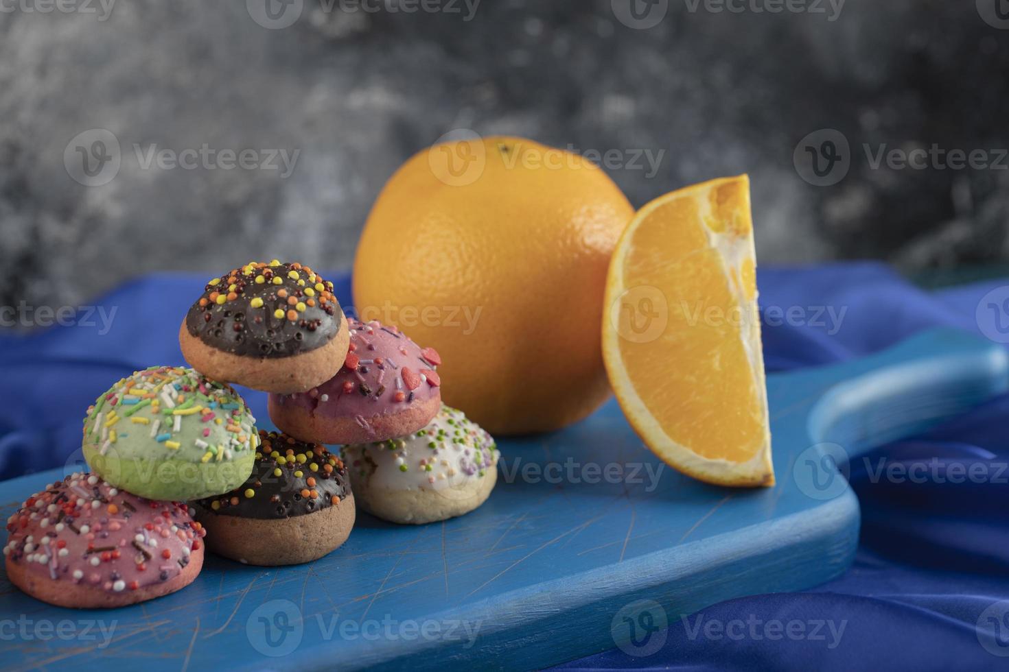 Colorful sweet doughnuts with sliced orange photo