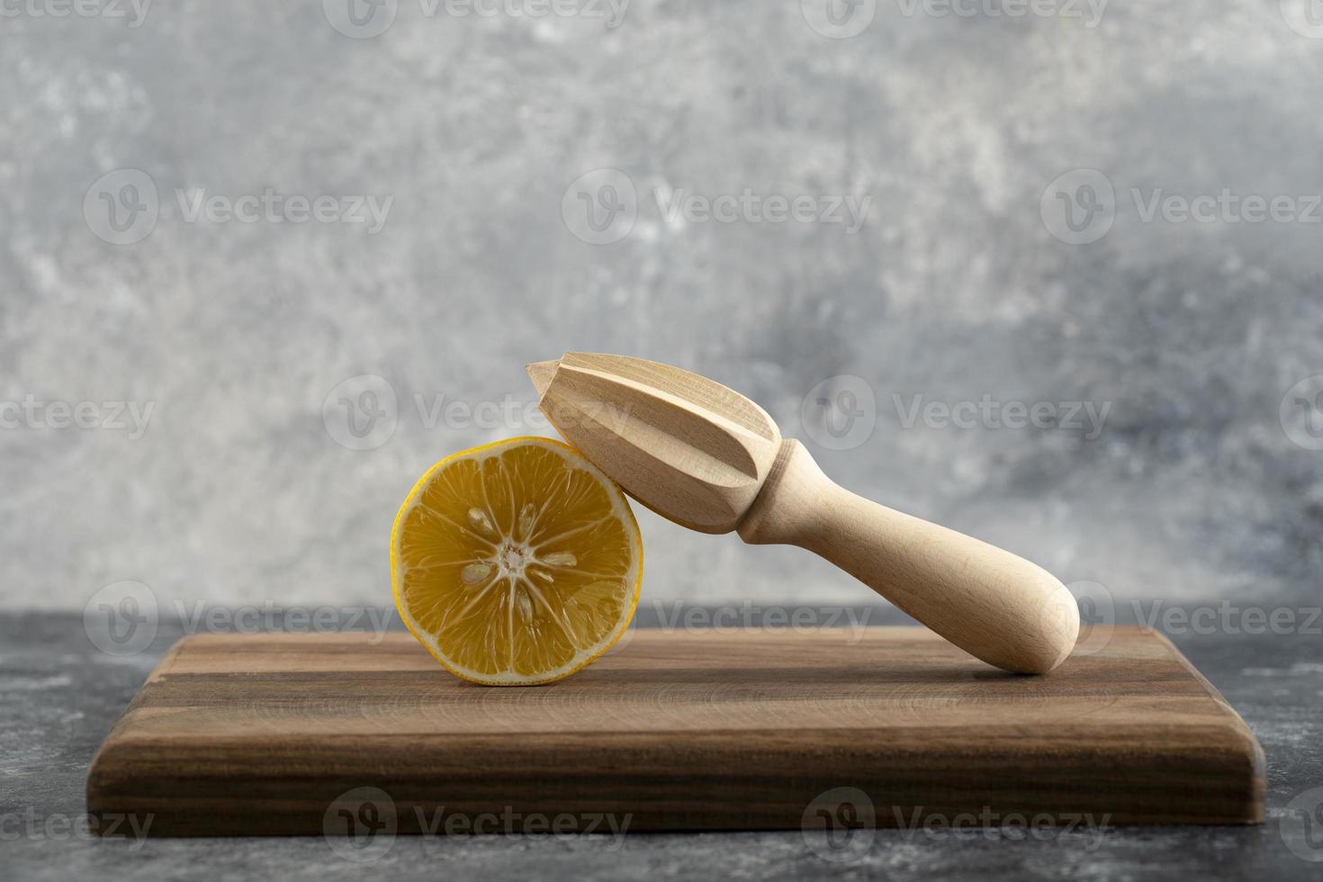 Limón en rodajas con un escariador de madera sobre una tabla de madera foto