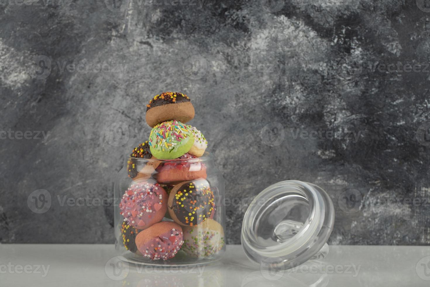 un frasco de vidrio lleno de pequeñas rosquillas de colores foto