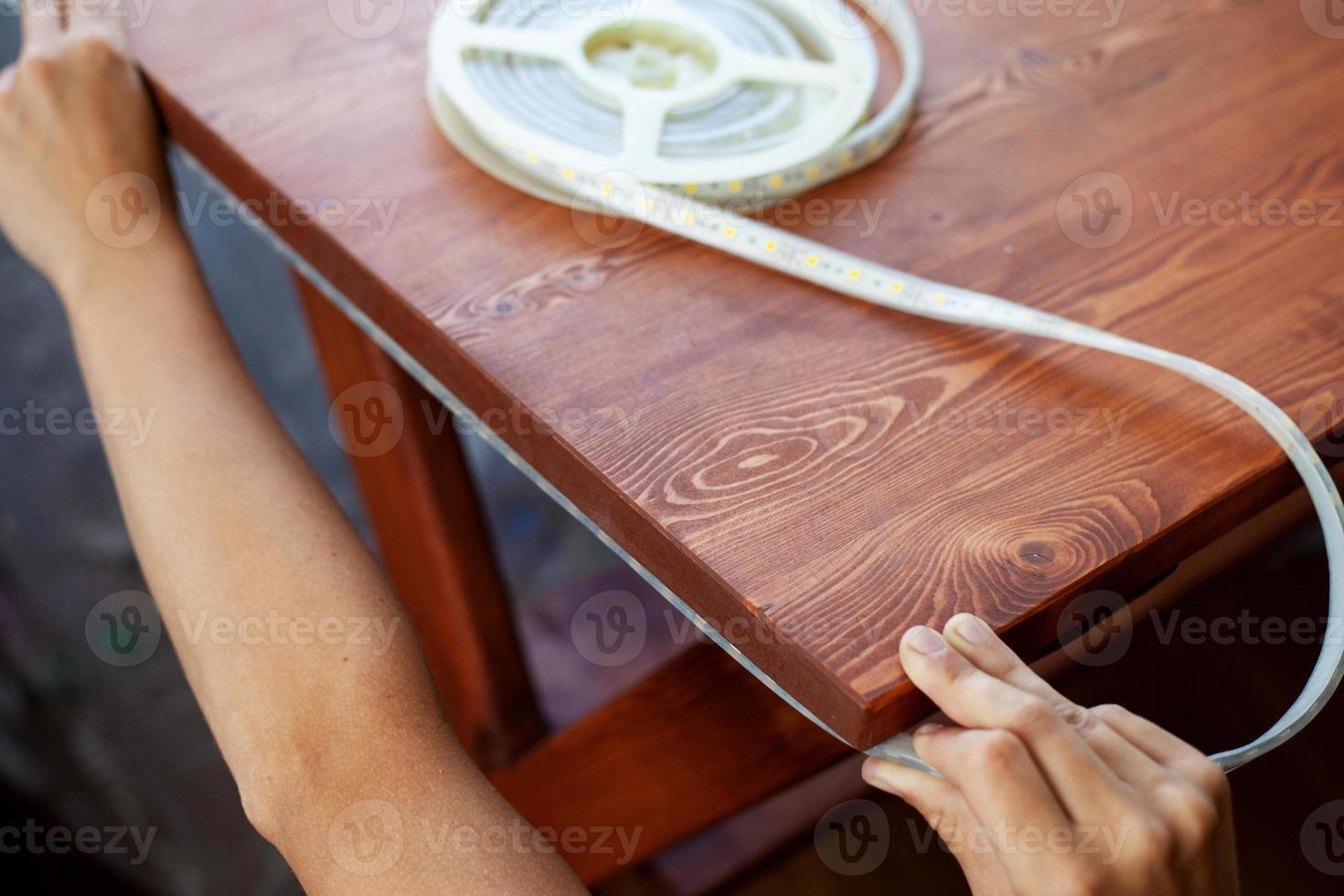 persona poniendo una tira de led en una mesa foto