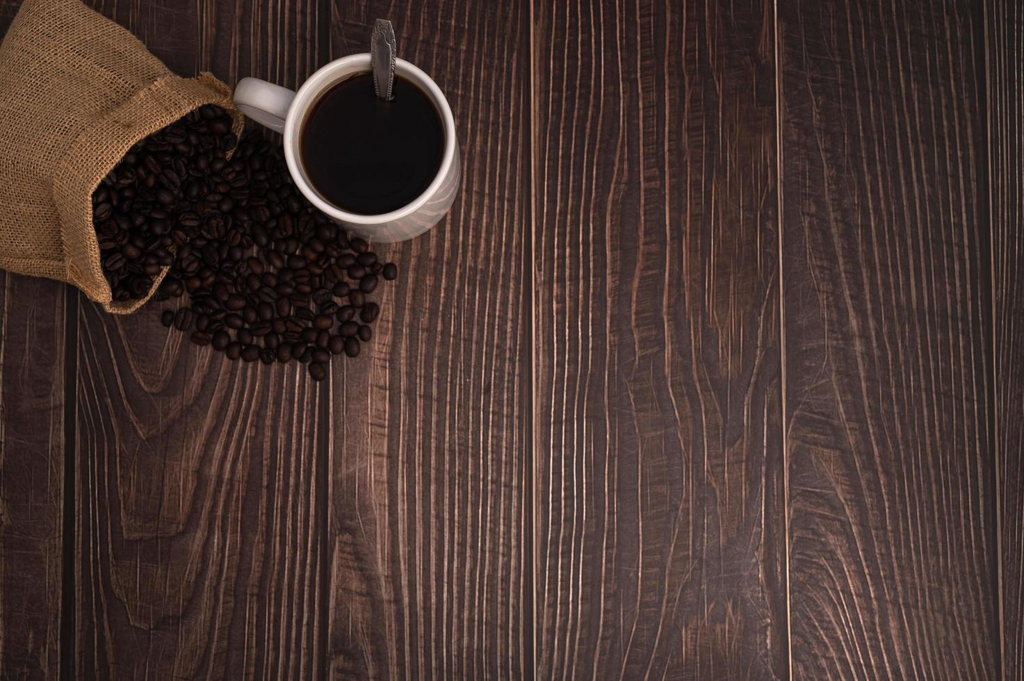 una taza de café y granos de café en una mesa de madera, amor concepto de café foto