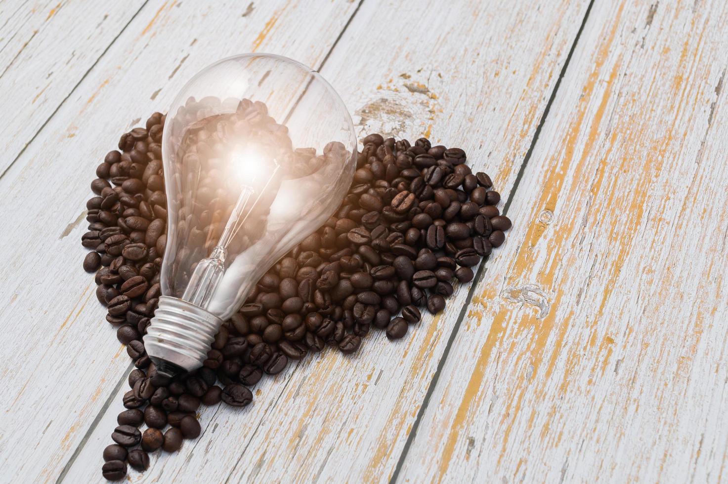 Coffee beans in heart shape and a lightbulb on a wooden table photo