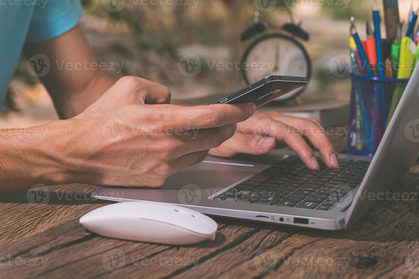 Man using laptop and mobile phone on wooden table photo