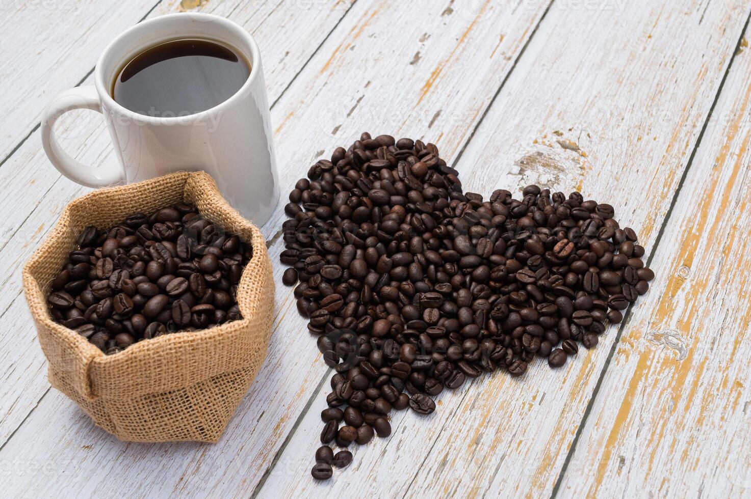 Coffee beans and heart shape on white wooden table photo