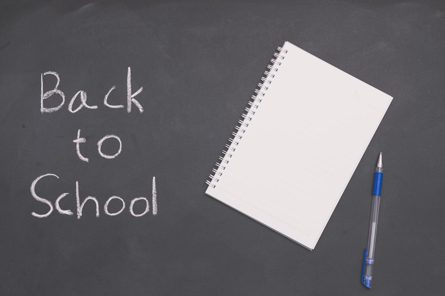 Un cuaderno blanco con un bolígrafo en una pizarra, regreso a la escuela y el concepto de educación foto