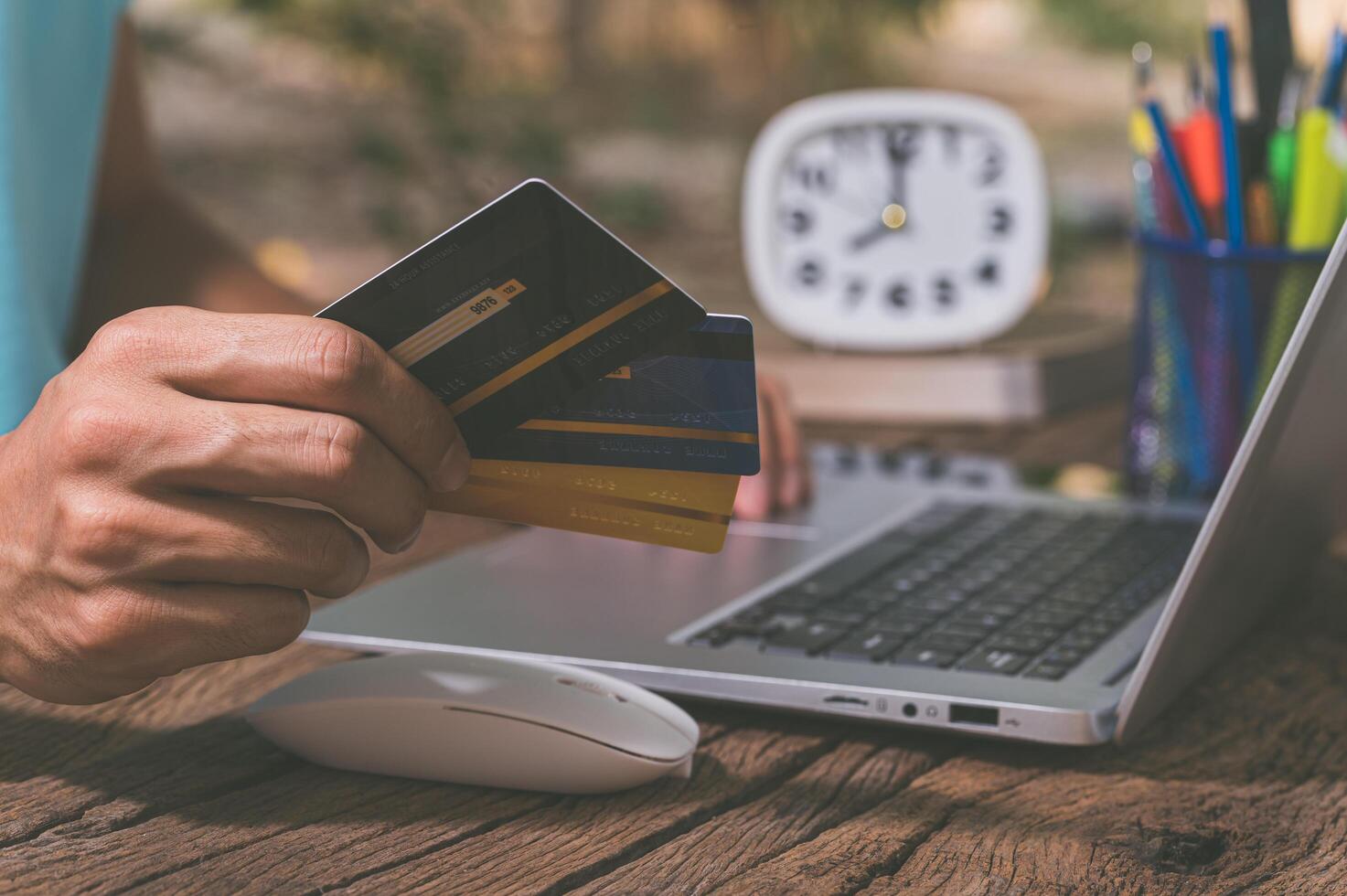 A person holding a credit card to shop online through a notebook computer photo