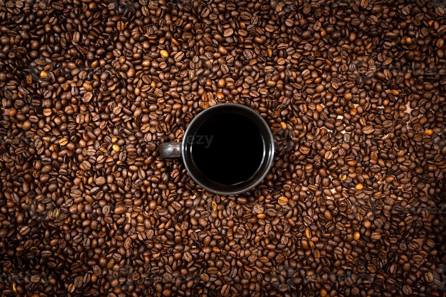 Vista superior de la taza de café negro en el fondo de los granos de café foto