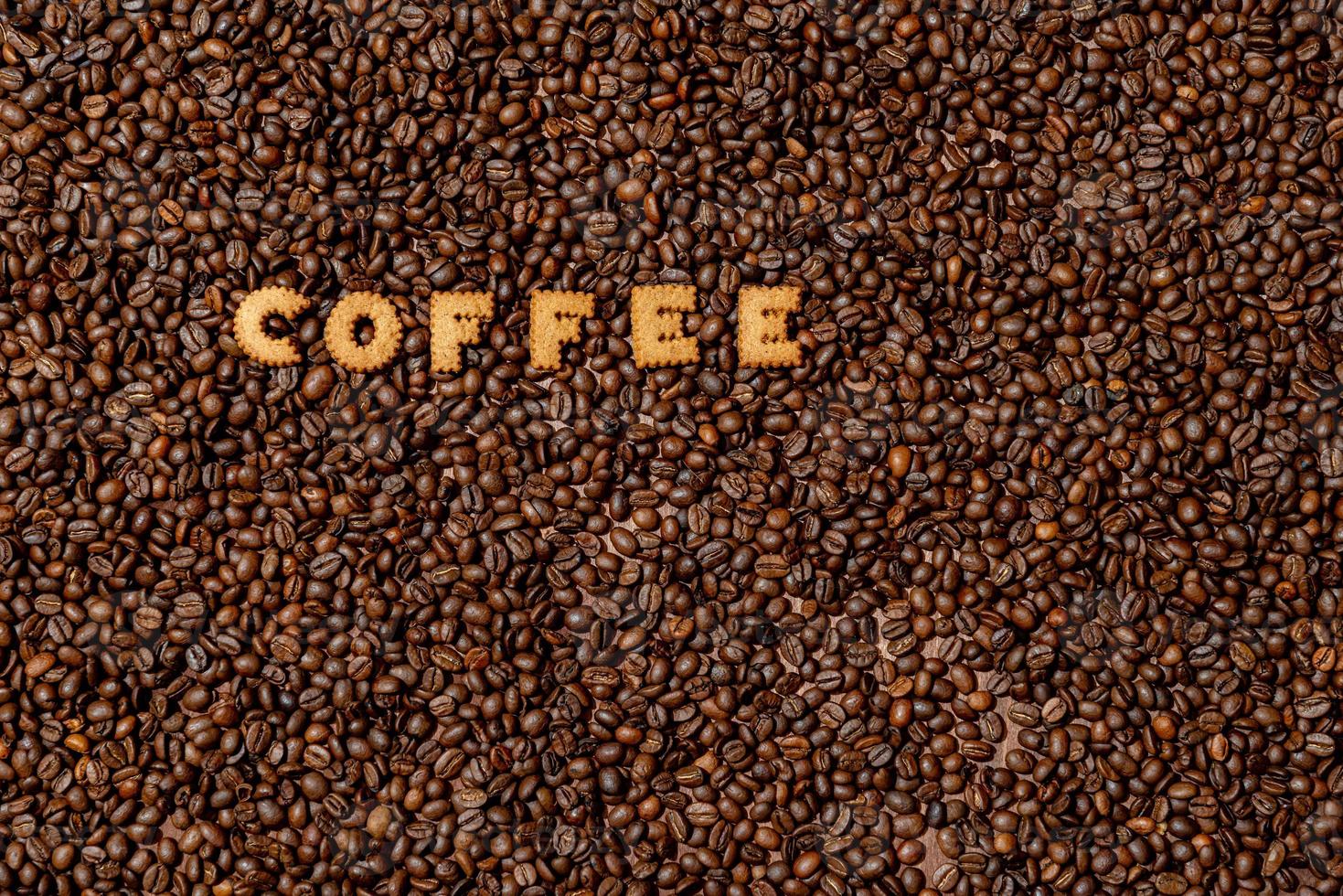 The word COFFEE made from biscuit letters on a dark coffee bean background photo