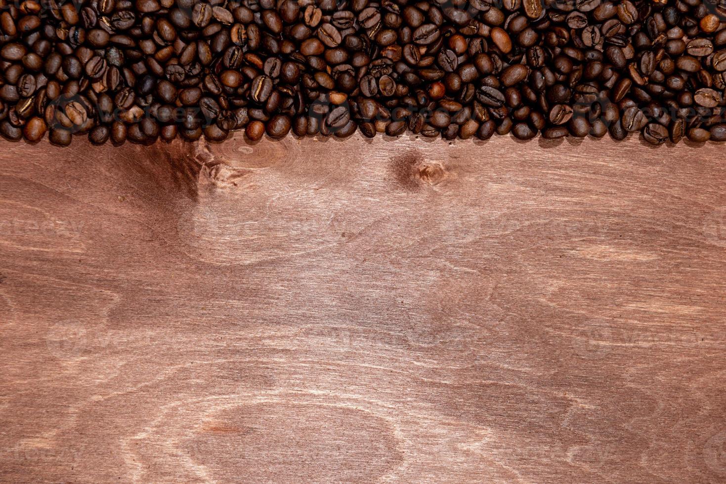 Raya de granos de café sobre fondo de textura de madera oscura, espacio para copiar texto foto