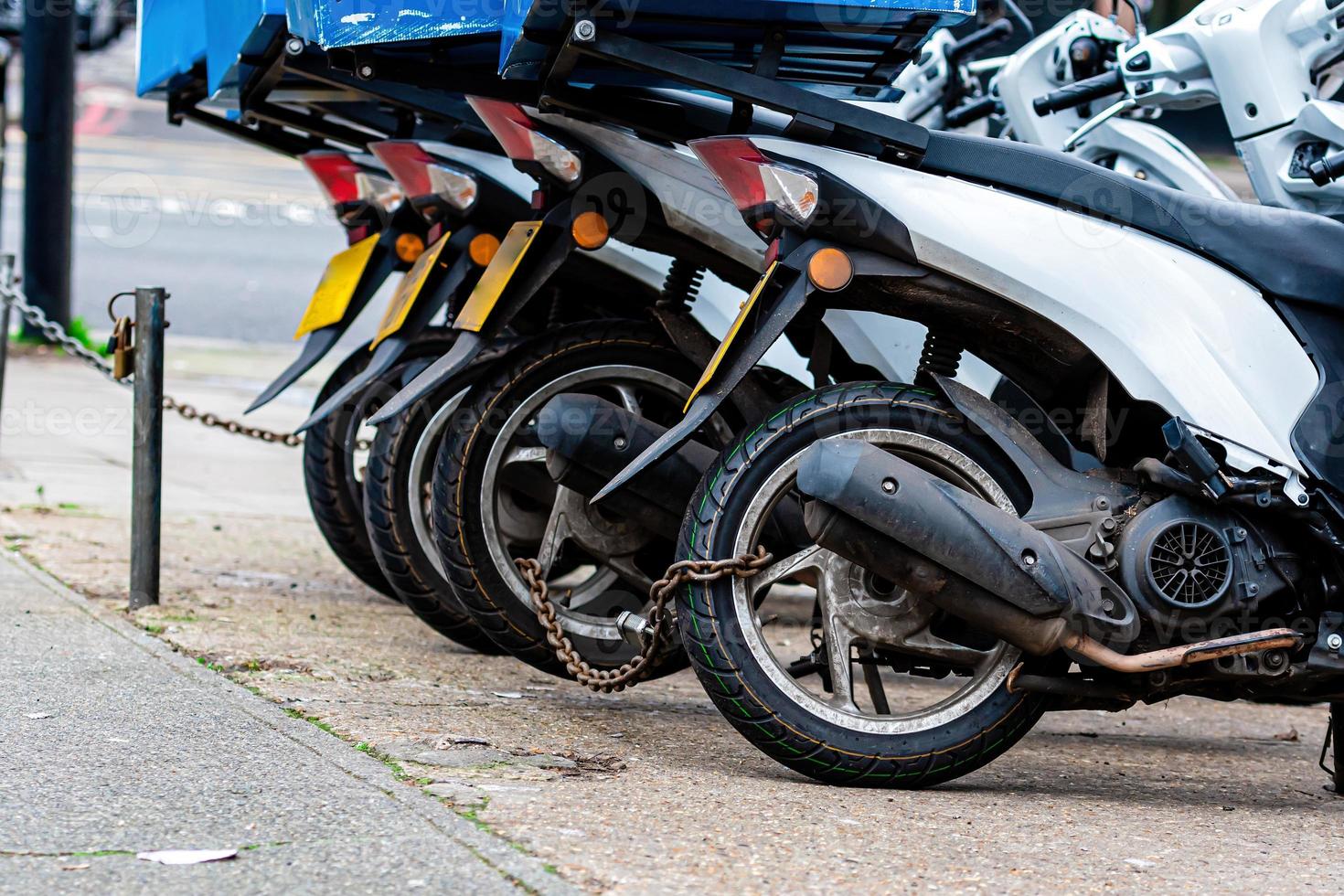 The rear wheels of the pizza delivery scooter chain are locked with an anti-theft chain photo