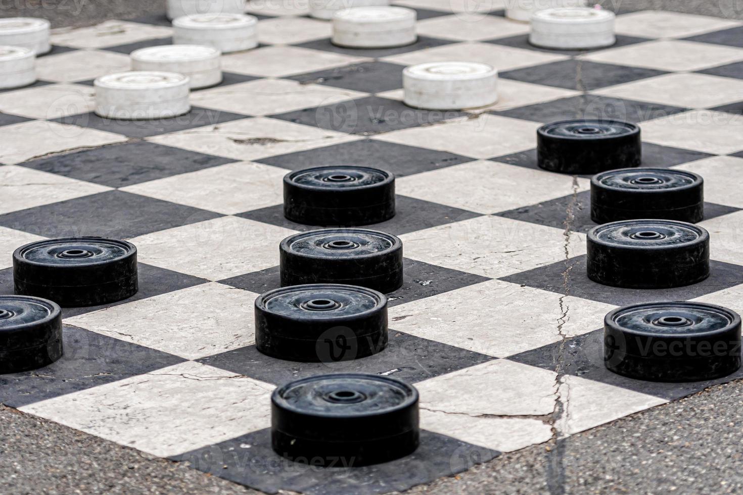 Large plastic checkers painted on the pavement cells in a city park photo