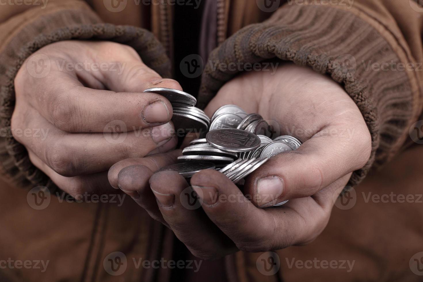 monedas en manos del mendigo foto