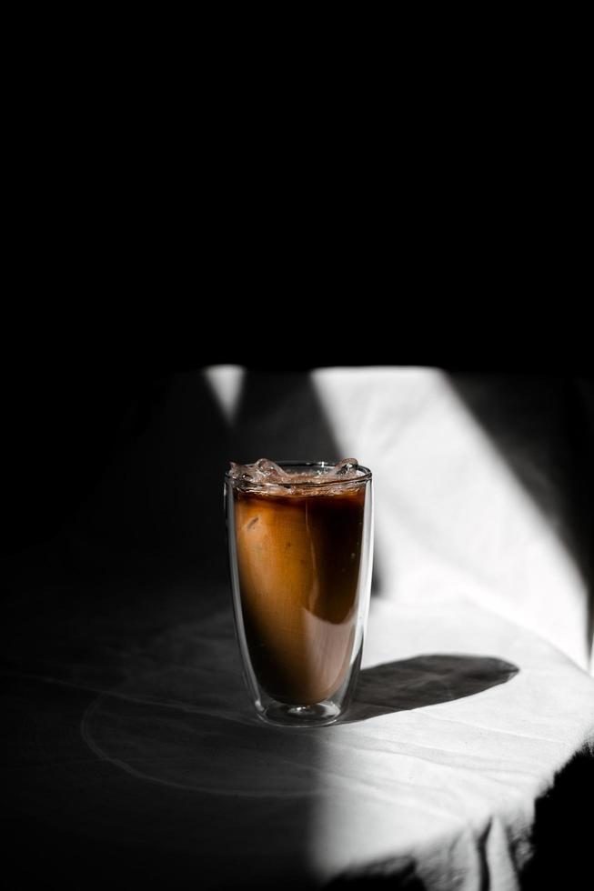 Iced coffee with milk on the table in dramatic lighting photo