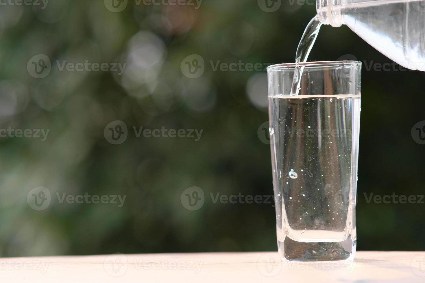 Agua potable mineral en la mesa de madera y agua en vidrio foto