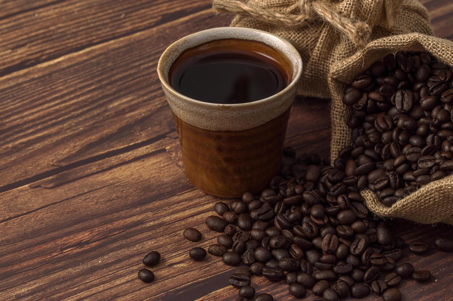 una taza de café y granos de café en una mesa de madera foto