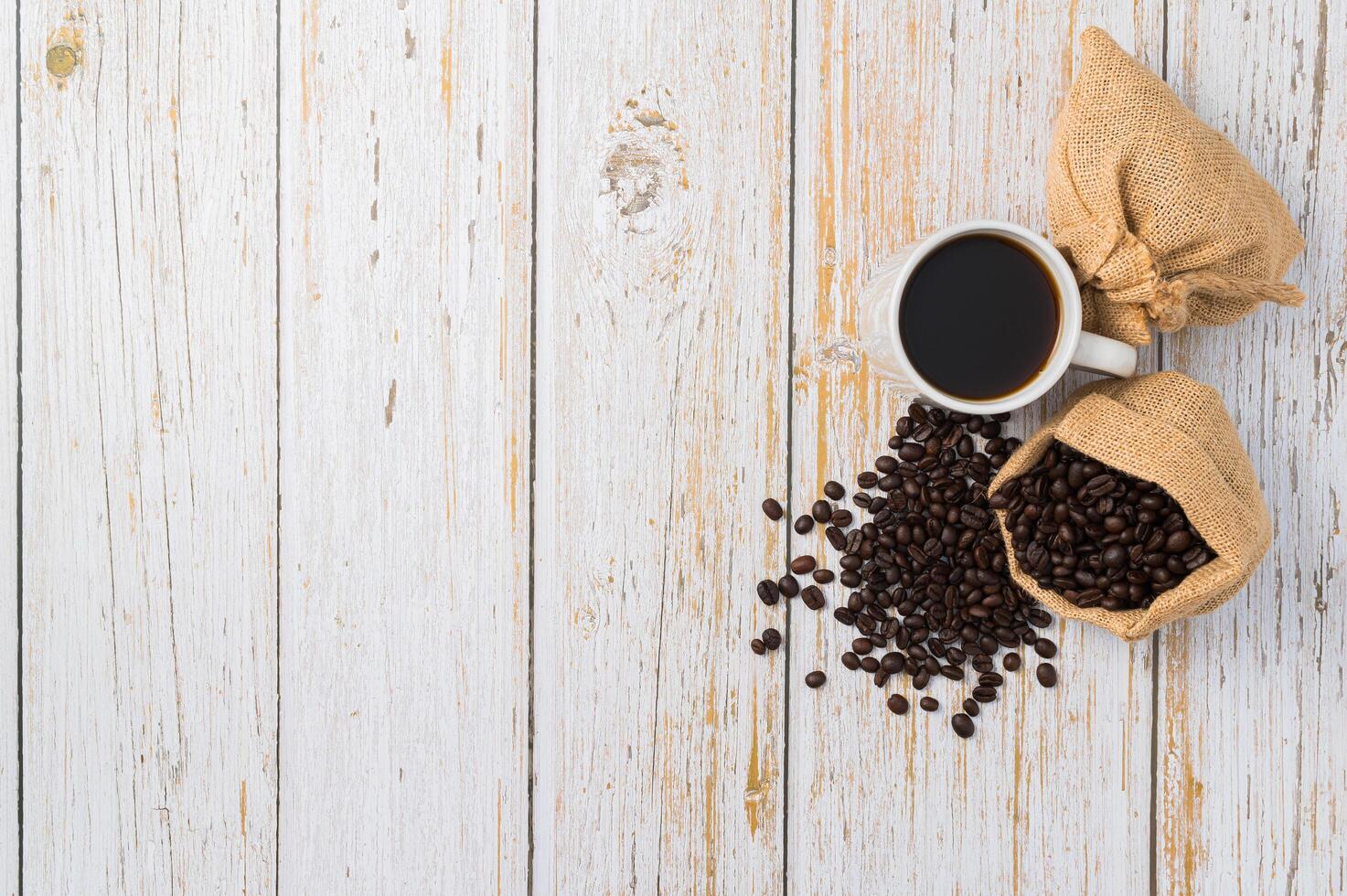 una taza de café y granos de café en una mesa de madera foto