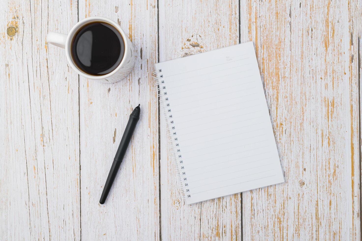 café y un cuaderno con un bolígrafo en un escritorio de madera foto