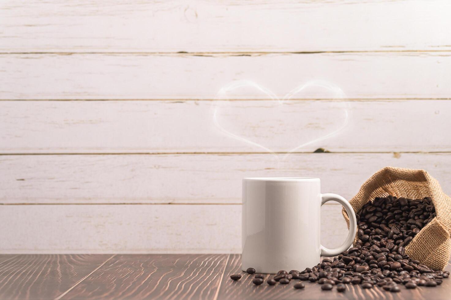 A coffee mug making heart-shaped steam with a bag of coffee beans on a wooden table photo