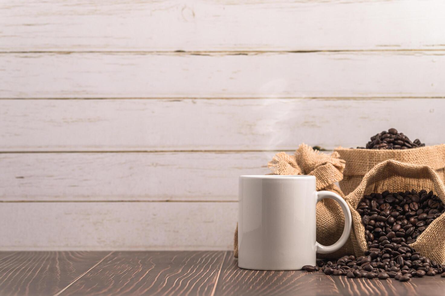 una taza de café y bolsas de granos de café en una mesa de madera foto