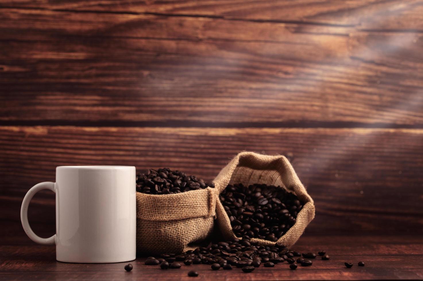 una taza de café y bolsas de granos de café en una mesa de madera foto