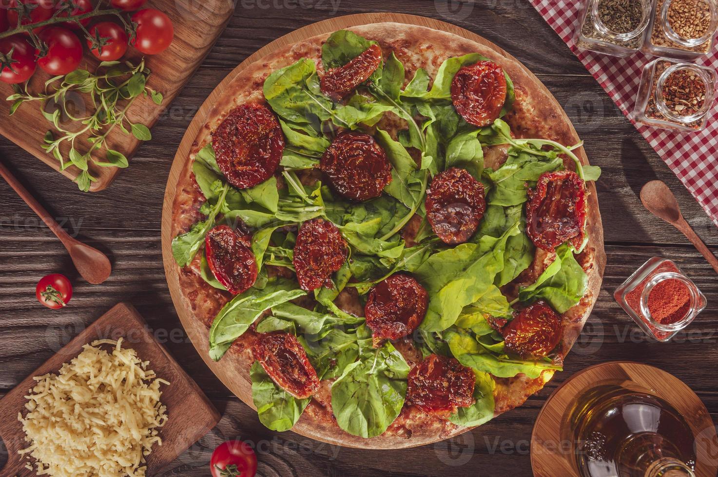 Brazilian pizza with tomato sauce, mozzarella, arugula, dried tomatoes and oregano photo