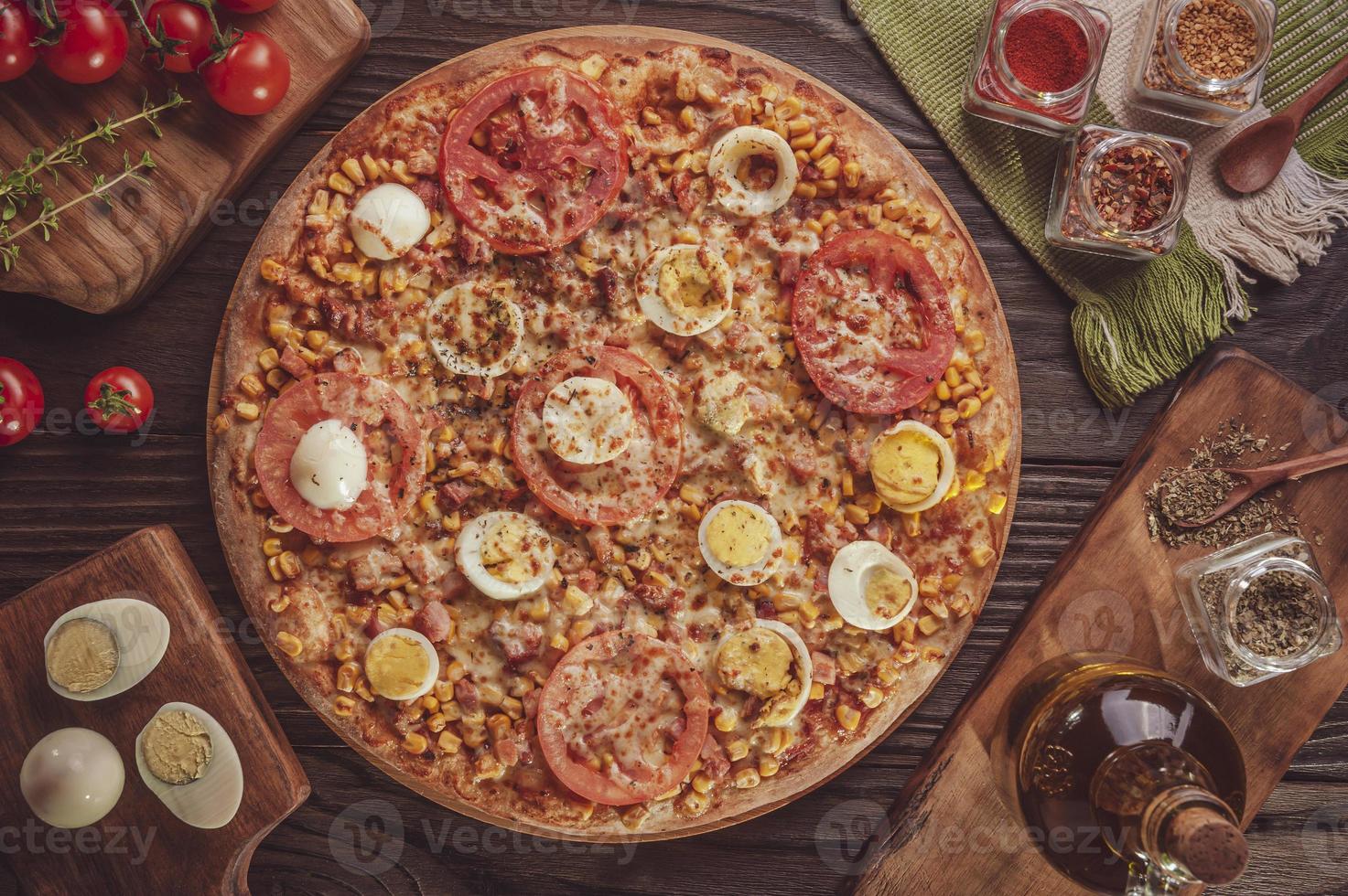 pizza brasileña con mozzarella, maíz, tocino, huevos, tomate y orégano foto