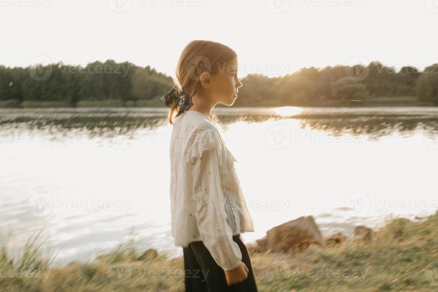 A blurred portrait of a young girl who is watching straight and walking on the coast photo