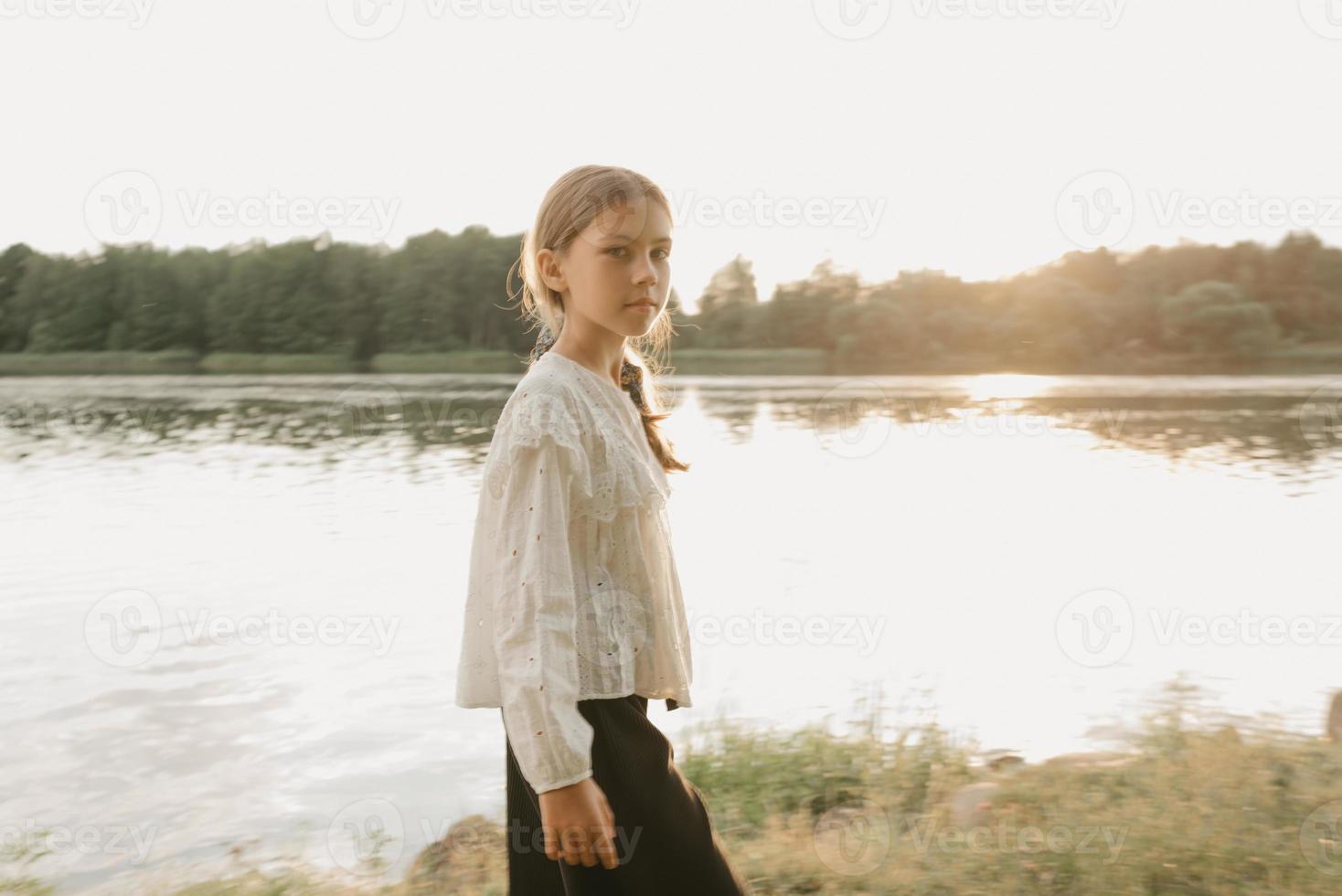 A blurred portrait of a young girl who is watching straight and walking on the coast photo