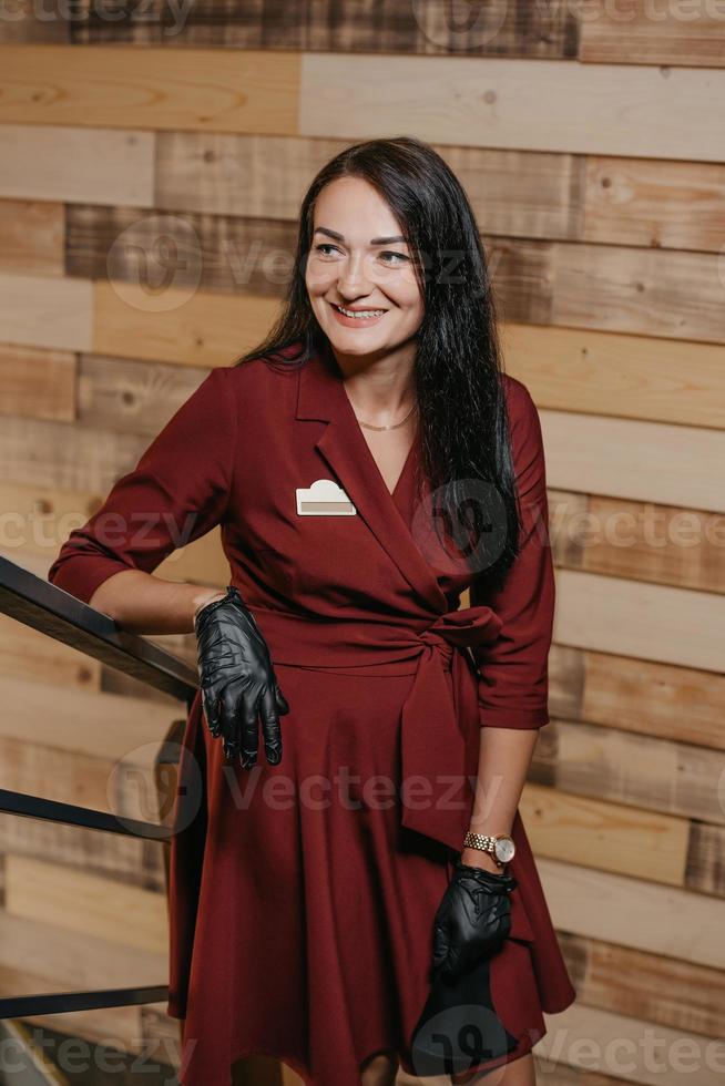 A laughing female restaurant manager in black disposable gloves posing in a coffee shop photo