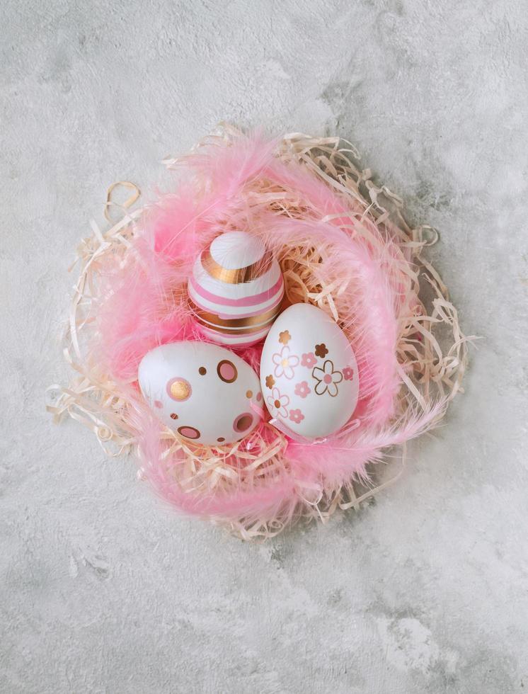 Easter painted eggs and pink feathers on a marble background photo