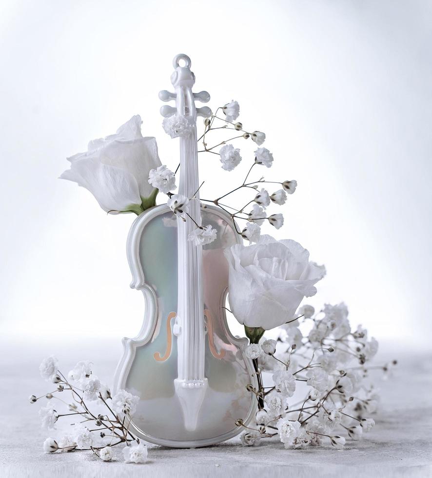 White artificial violin and white flower buds on a white background photo