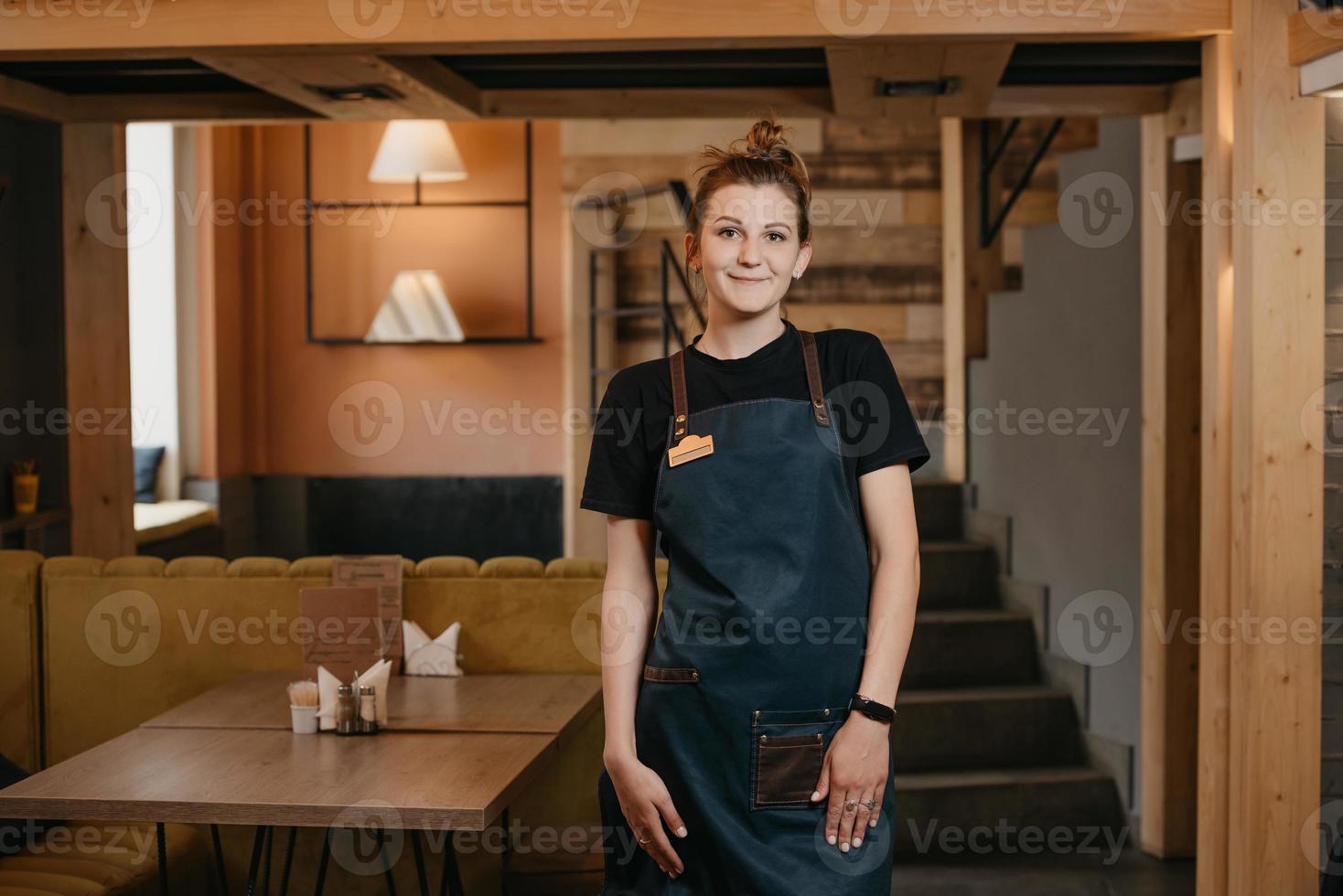 A young smiling waitress is posing in a restaurant photo