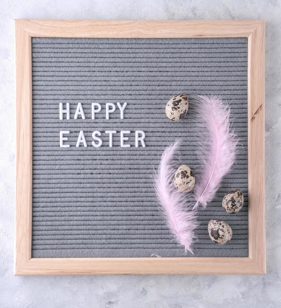 Letterboard with text Happy Easter, pink feathers, and eggs photo