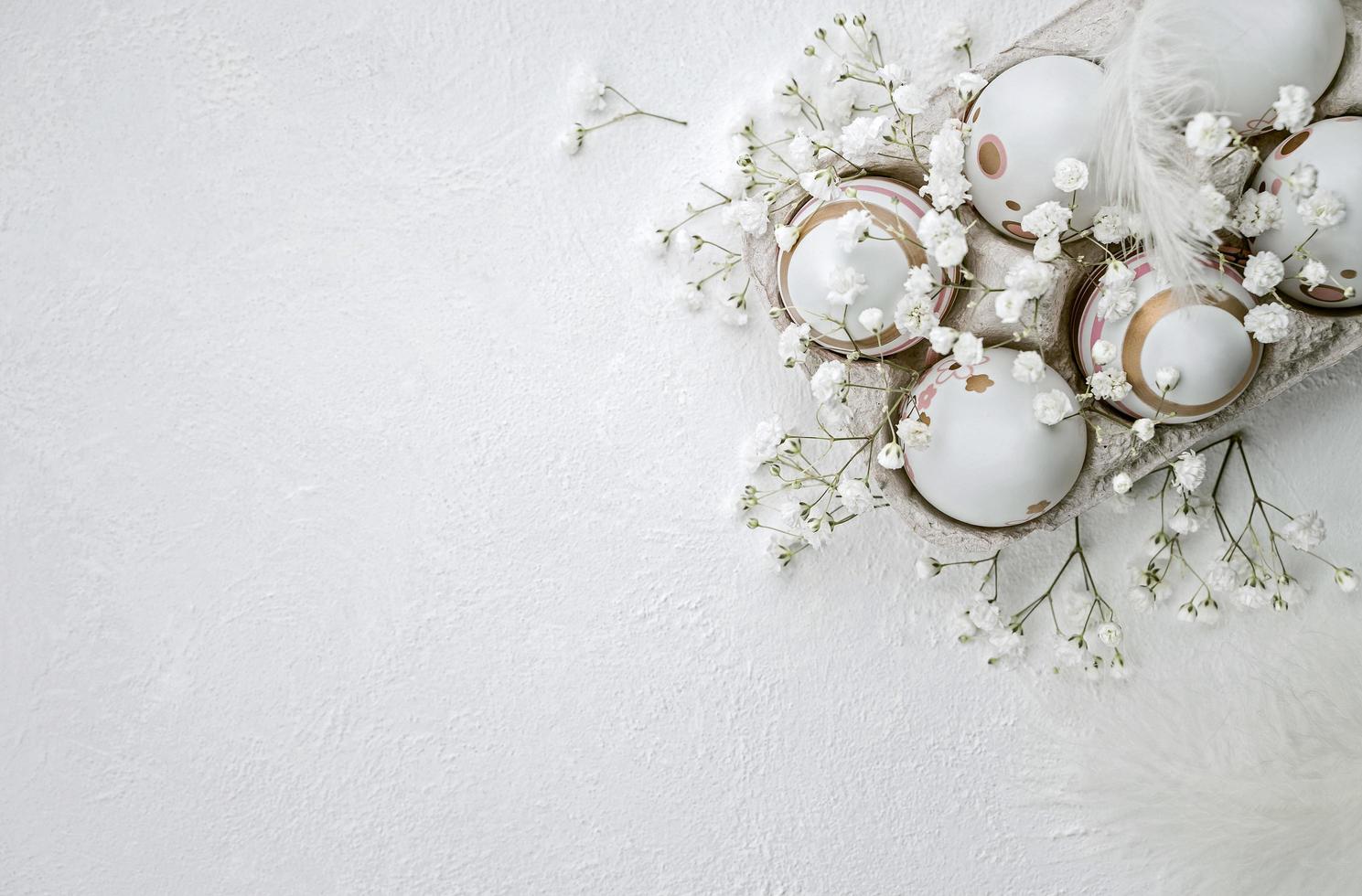 Easter-painted eggs, flowers, and feathers on a white textured background photo