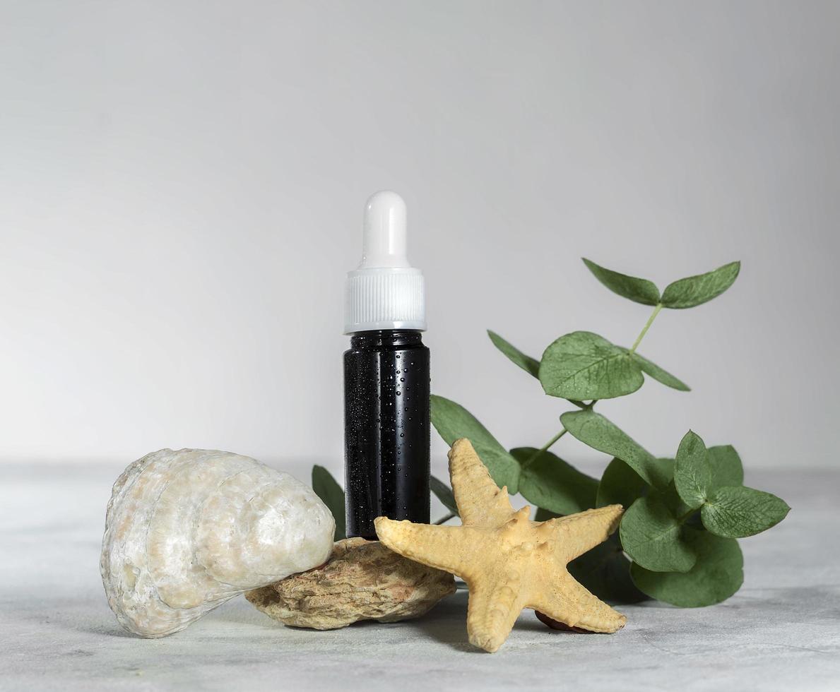 Amber glass bottle of essential oil or serum cosmetics with eucalyptus leaves, shells, and starfish photo