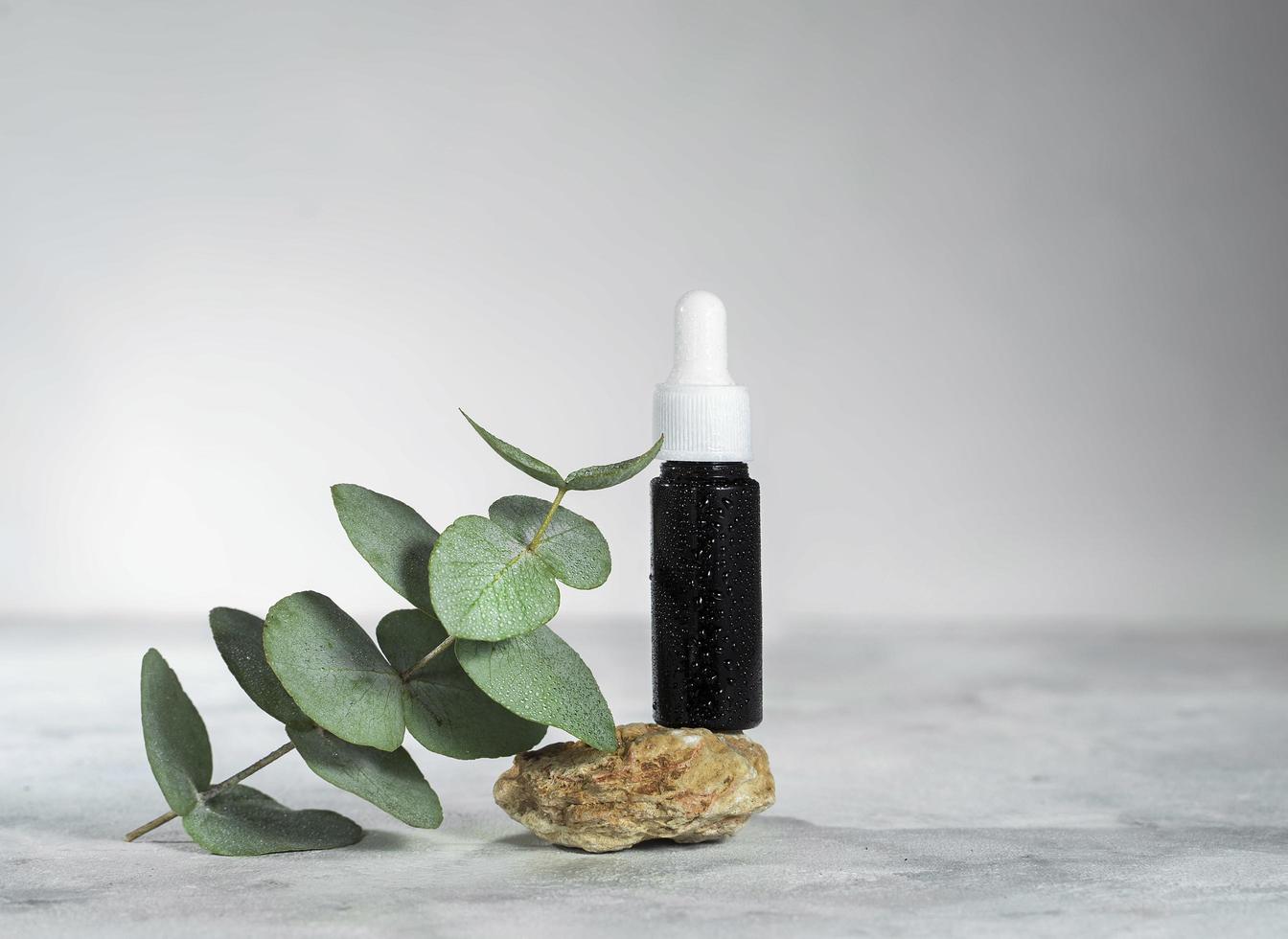 Amber glass bottle of essential oil or serum cosmetics with eucalyptus leaves, shells, and starfish photo