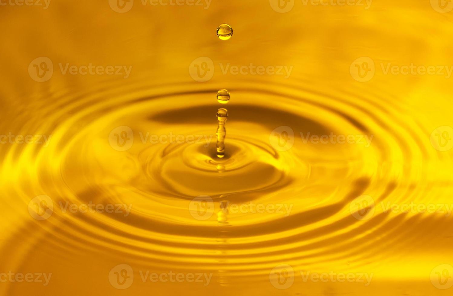 Drops falling in water on yellow background photo