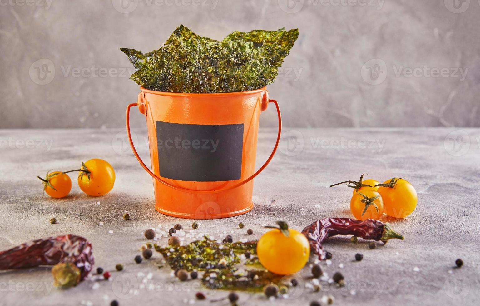 Alga nori crujiente con tomates cherry y especias en un cubo de naranja foto