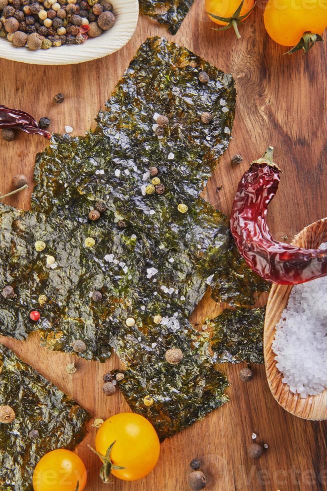 Crujiente de algas nori con tomates cherry y especias sobre una tabla de madera foto