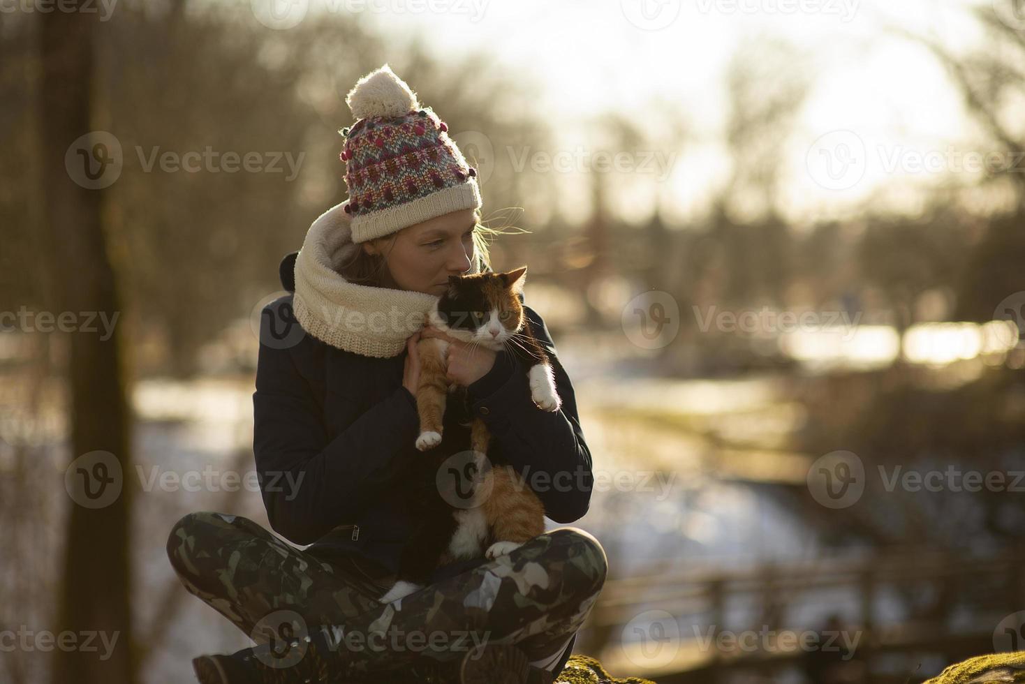 Una joven mujer atlética sosteniendo un gato al aire libre foto