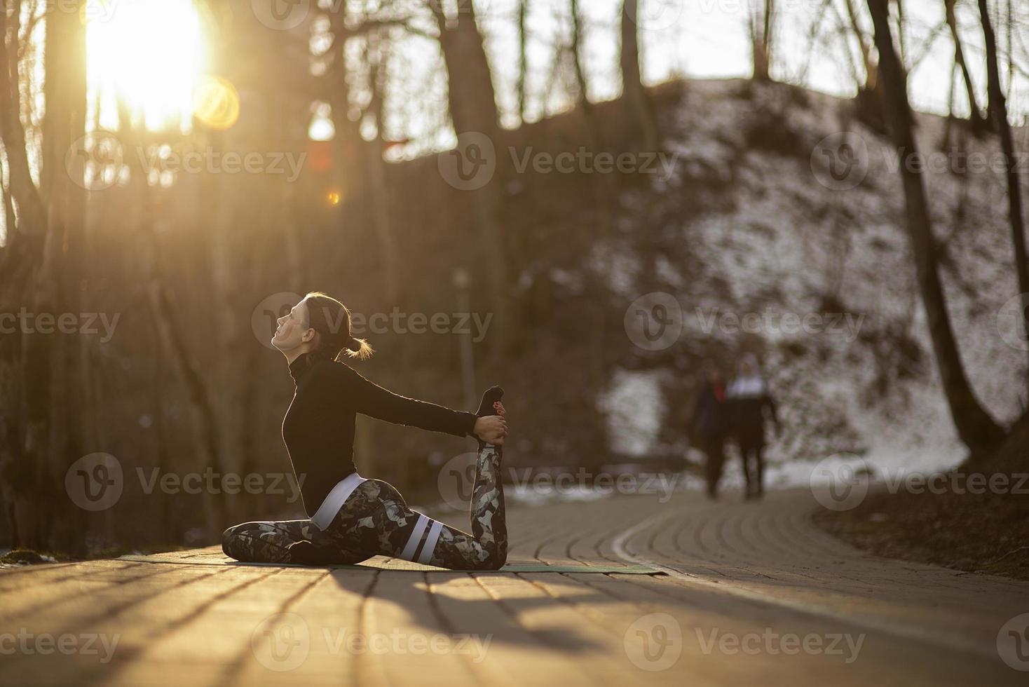 A young athletic woman performs yoga and meditation exercises outdoors photo