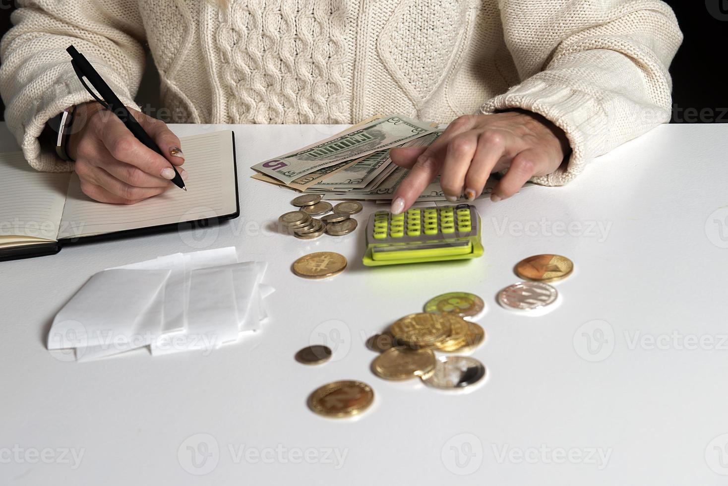 Close-up of a woman calculating money and writes in a notebook photo