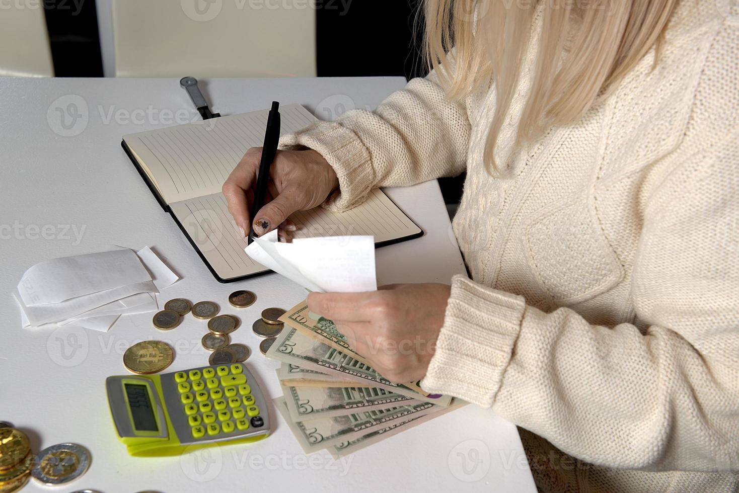 Close-up of a woman calculating money and writes in a notebook photo