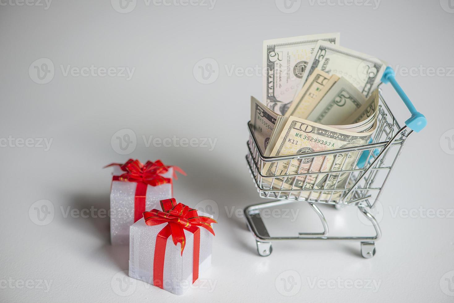 Shopping cart with money and gift boxes isolated photo