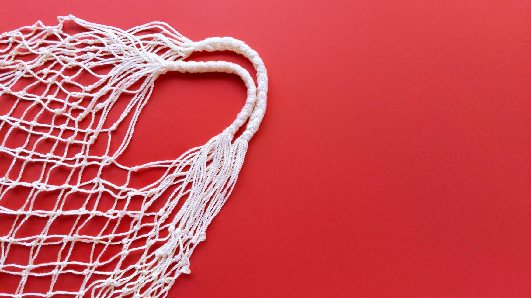 White string cotton eco bag on a red background, simple flat lay with copy space zero-waste concept photo