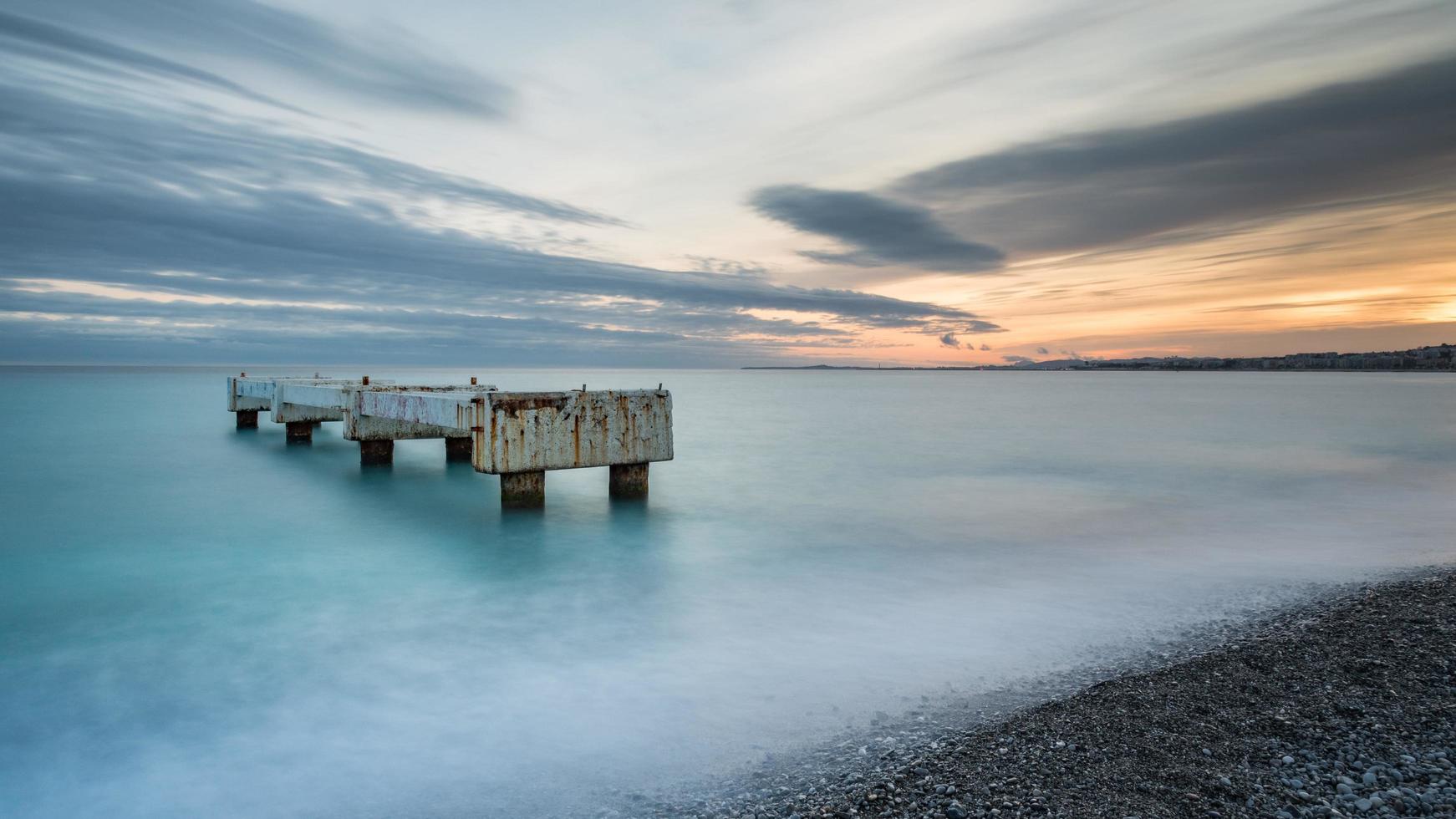 La larga exposición de una playa durante la puesta de sol en Niza, Francia foto