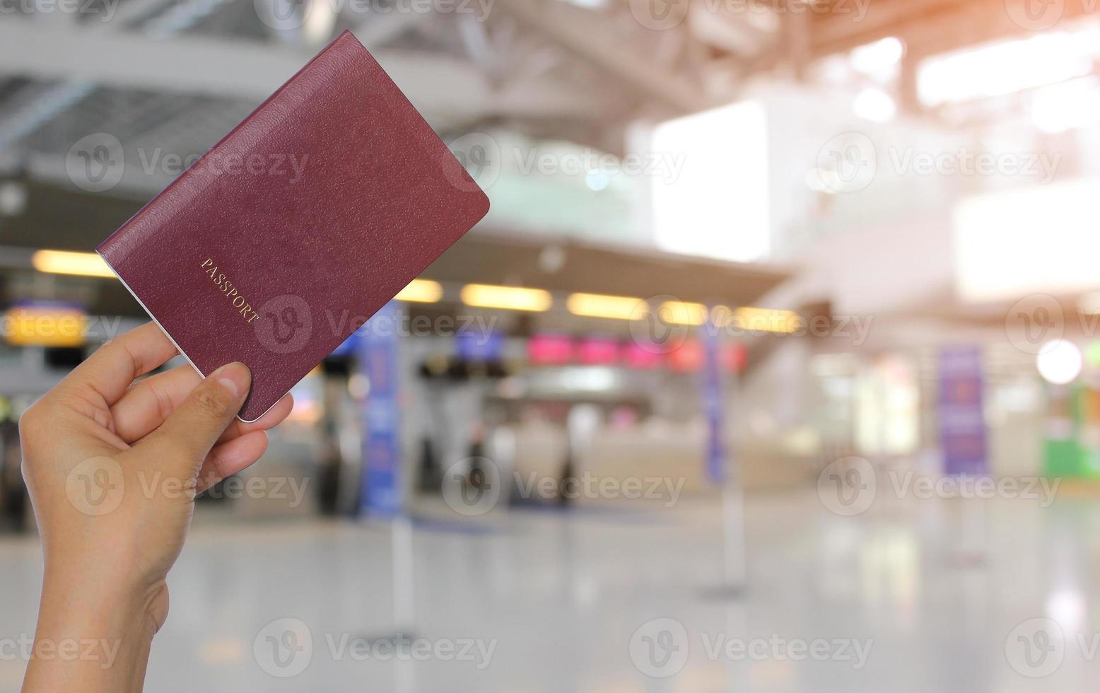 Primer plano de una niña sosteniendo un pasaporte con un fondo de aeropuerto, concepto de viaje foto