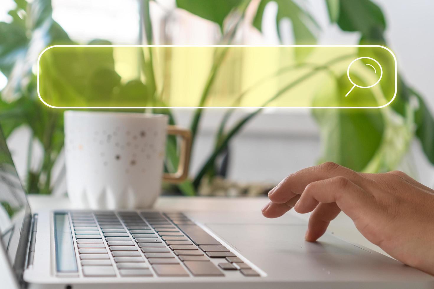 A hand using a laptop computer searching for information in the internet with a search box icon photo