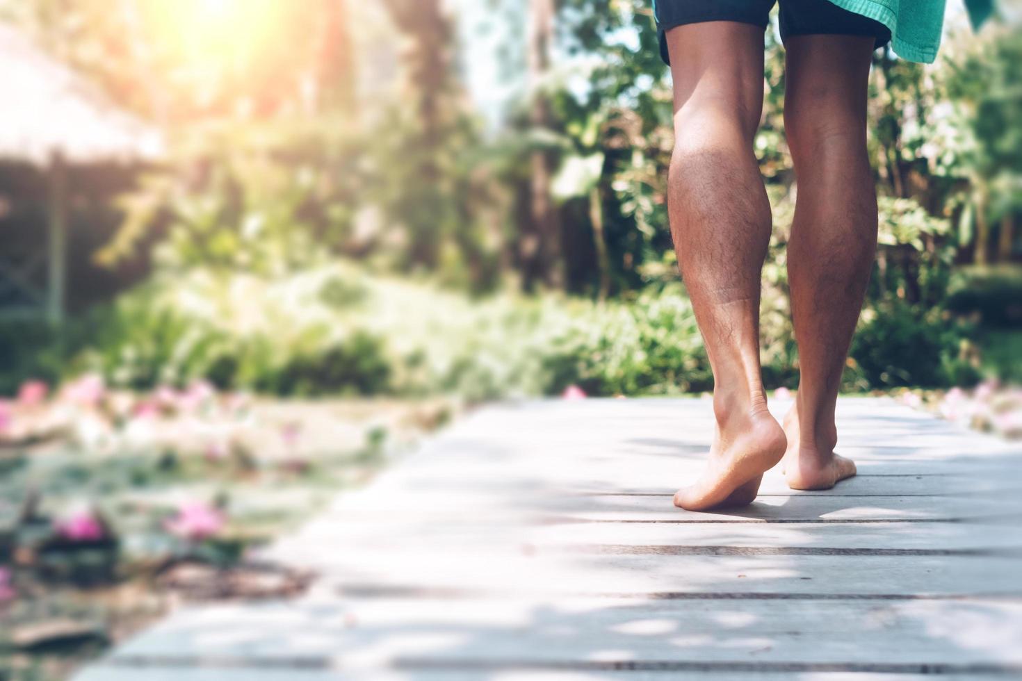 A person walking on a small wooden walkway with a sunlight flare in a tropical location photo